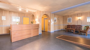 Un espace d’accueil comprenant un comptoir de réception en bois, un canapé et une table basse.