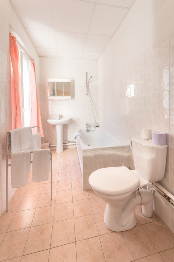 A bathroom with a toilet, sink, bathtub, and shower.