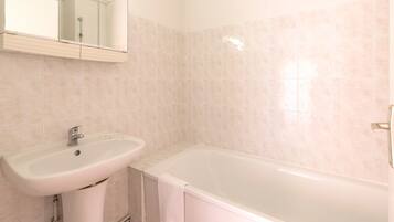Un baño con lavamanos, espejo y bañera.