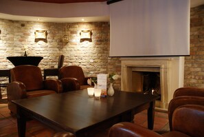 A conference room with a brick wall, a fireplace, and leather chairs. - Fletcher Hotel-Restaurant De Dikke Van Dale (Sluis)