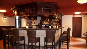 Een bar met een stenen toonbank, meerdere barkrukken en een divers assortiment flessen en glazen.