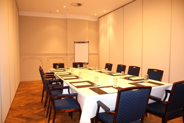 A conference room with a long table, chairs, and a whiteboard.
