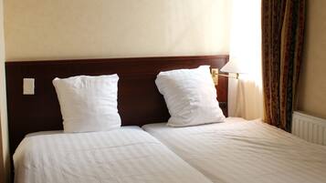 A double bed with white linens in a hotel room.