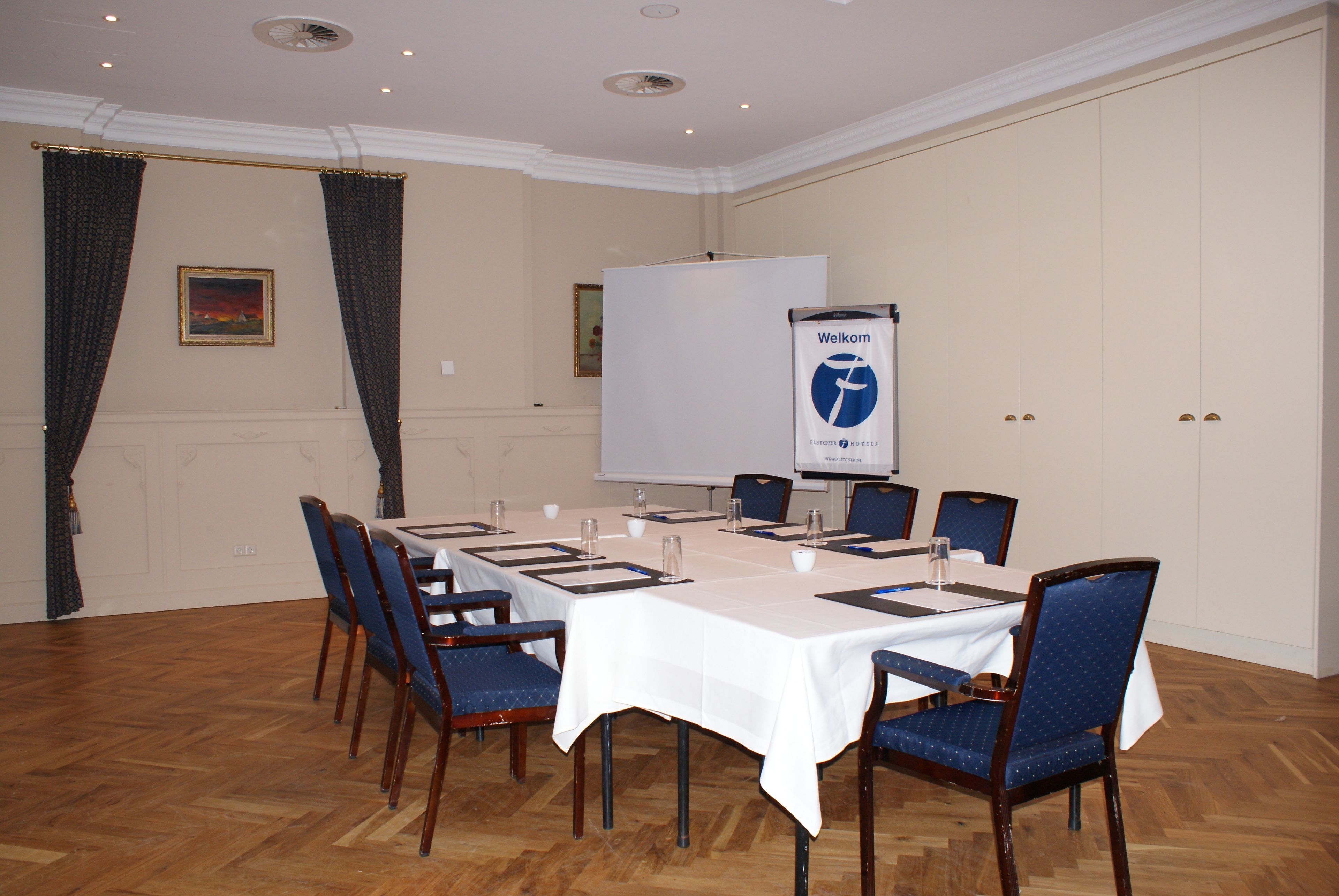Un salón de conferencias con una larga mesa, sillas, una pizarra y un cartel.