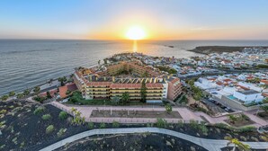 Ein Hotel an der Küste mit einem zentralen Innenhof, umgeben von einem Yachthafen und einem Strand.