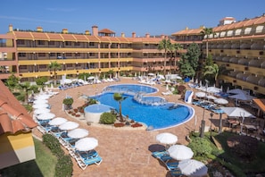 Un hotel con varias piscinas, tumbonas y sombrillas.