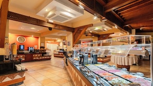 Ein Buffetbereich mit verschiedenen Speisen, einer Kaffeestation und einer Wanduhr.