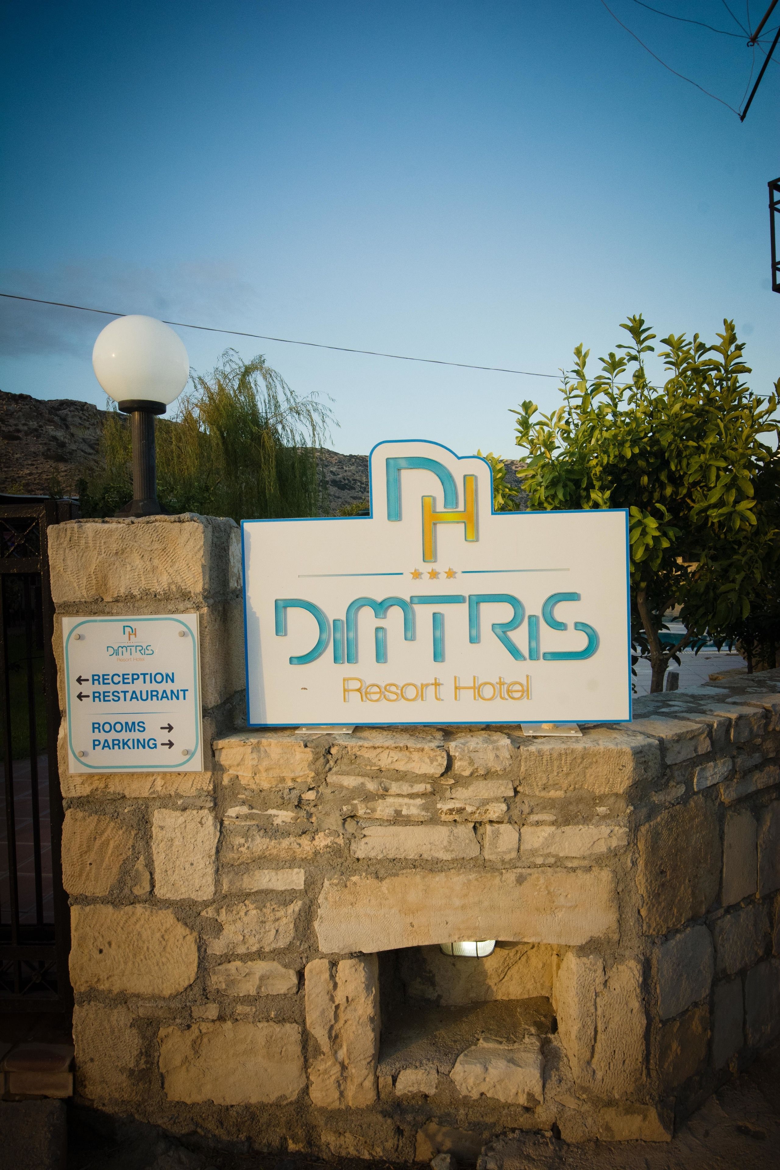 Un panneau indiquant l’hôtel Dimtris Resort, avec des indications pour se rendre à la réception, au restaurant, aux chambres et au parking.