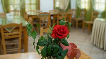 Un comedor con una mesa de madera, sillas y un florero con una rosa roja.