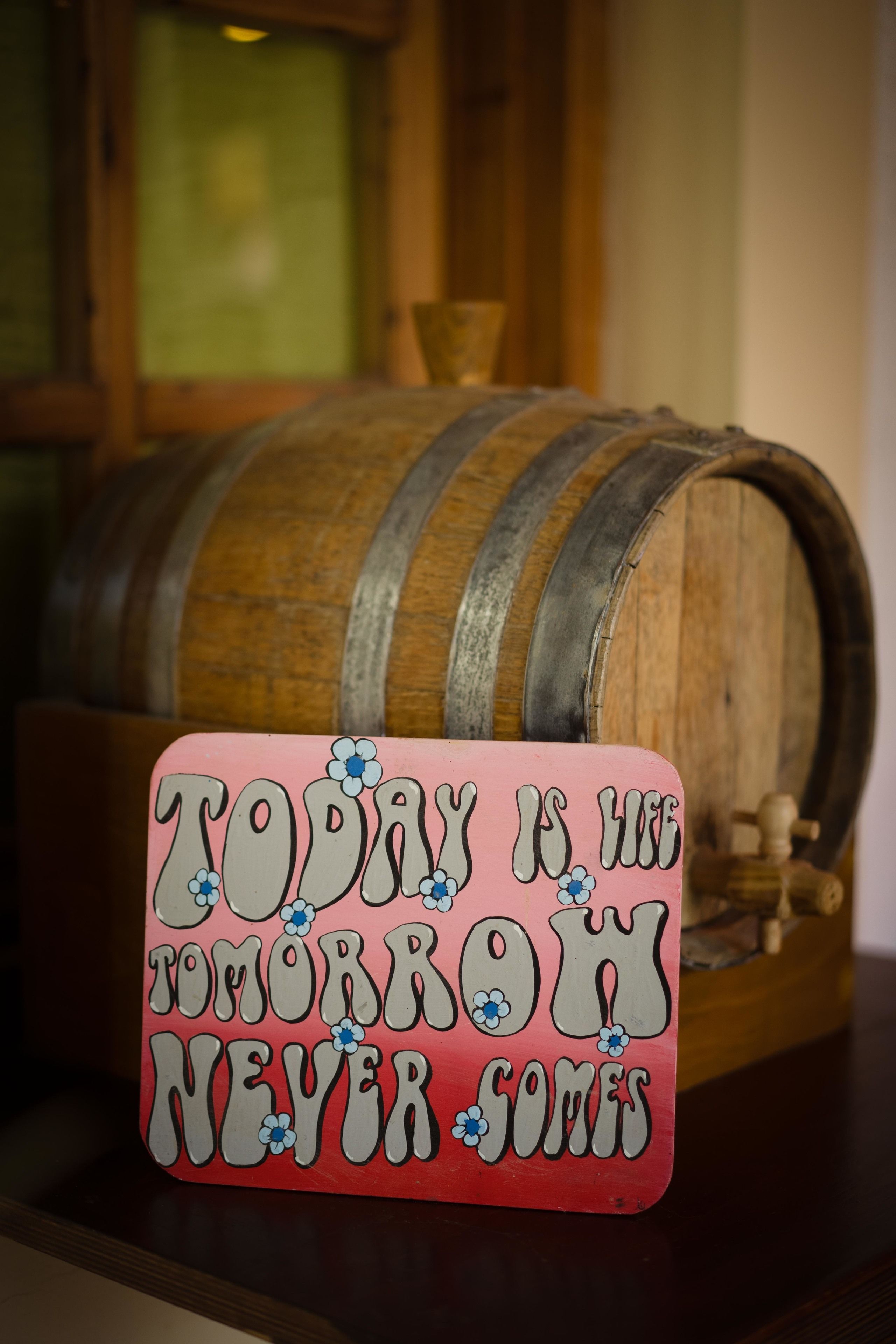 Een motiverende bord met de tekst 'TODAY IS THE TOMORROW NEVER SOMES' voor een houten vat.
