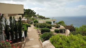A coastal property with a paved pathway leading to a building, surrounded by greenery and overlooking the sea. - Sun Club El Dorado (Llucmajor)