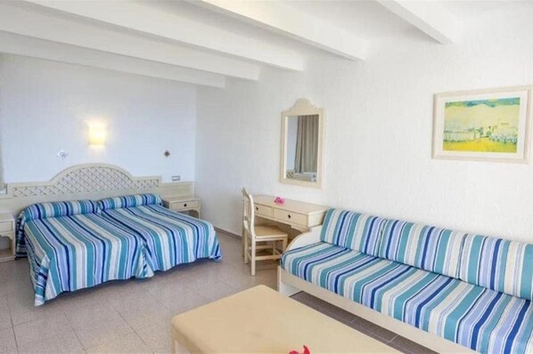 A hotel room with two beds, a desk, a sofa, a mirror, and a painting on the wall. - Sun Club El Dorado (Llucmajor)