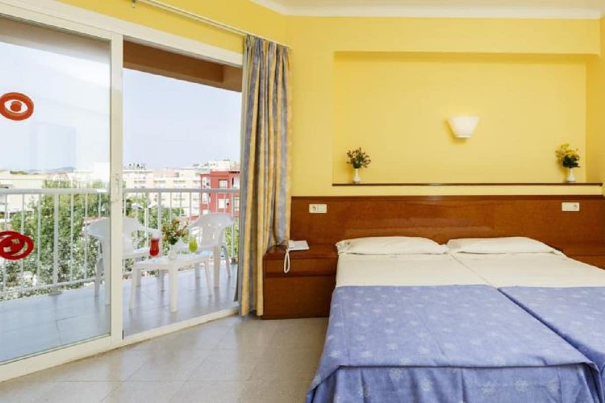 Hotellihuone, jossa on sänky, yöpöytä ja liukuoven kautta avautuva näkymä ulos.