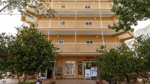 Un hôtel à plusieurs étages doté de balcons, d’un bar servant des collations et d’un panneau indiquant la présence d’un terrain de golf sur la plage.