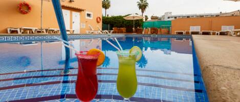 Una piscina al aire libre, sombrillas, tumbonas