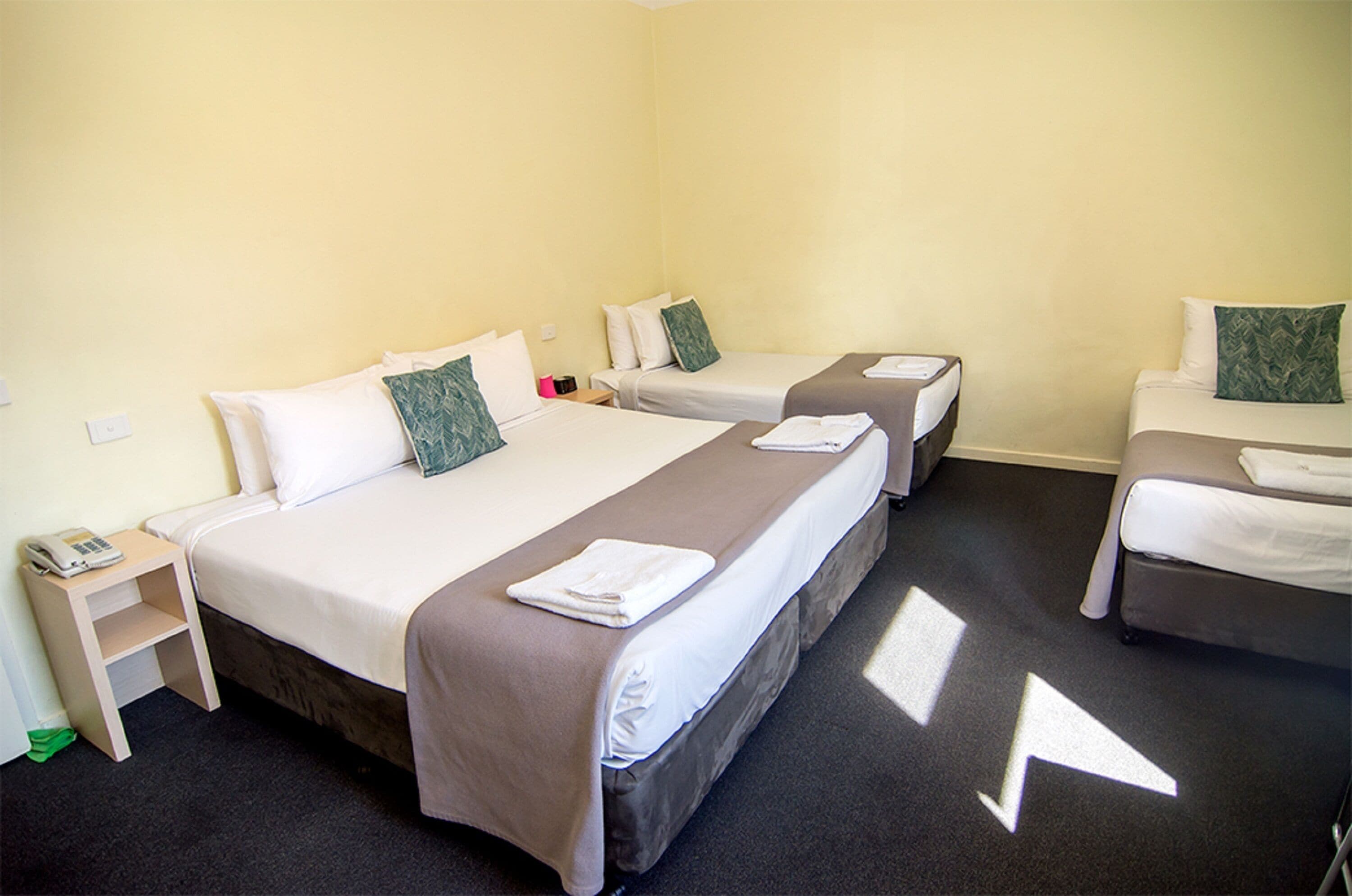 A hotel room with two single beds, a small desk with a telephone, and a chair.