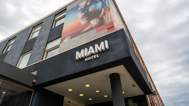 Un edificio moderno con un gran cartel publicitario del Hotel Miami.
