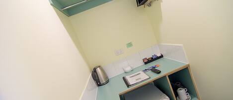 A kitchenette with a coffee maker, kettle, and a small refrigerator.