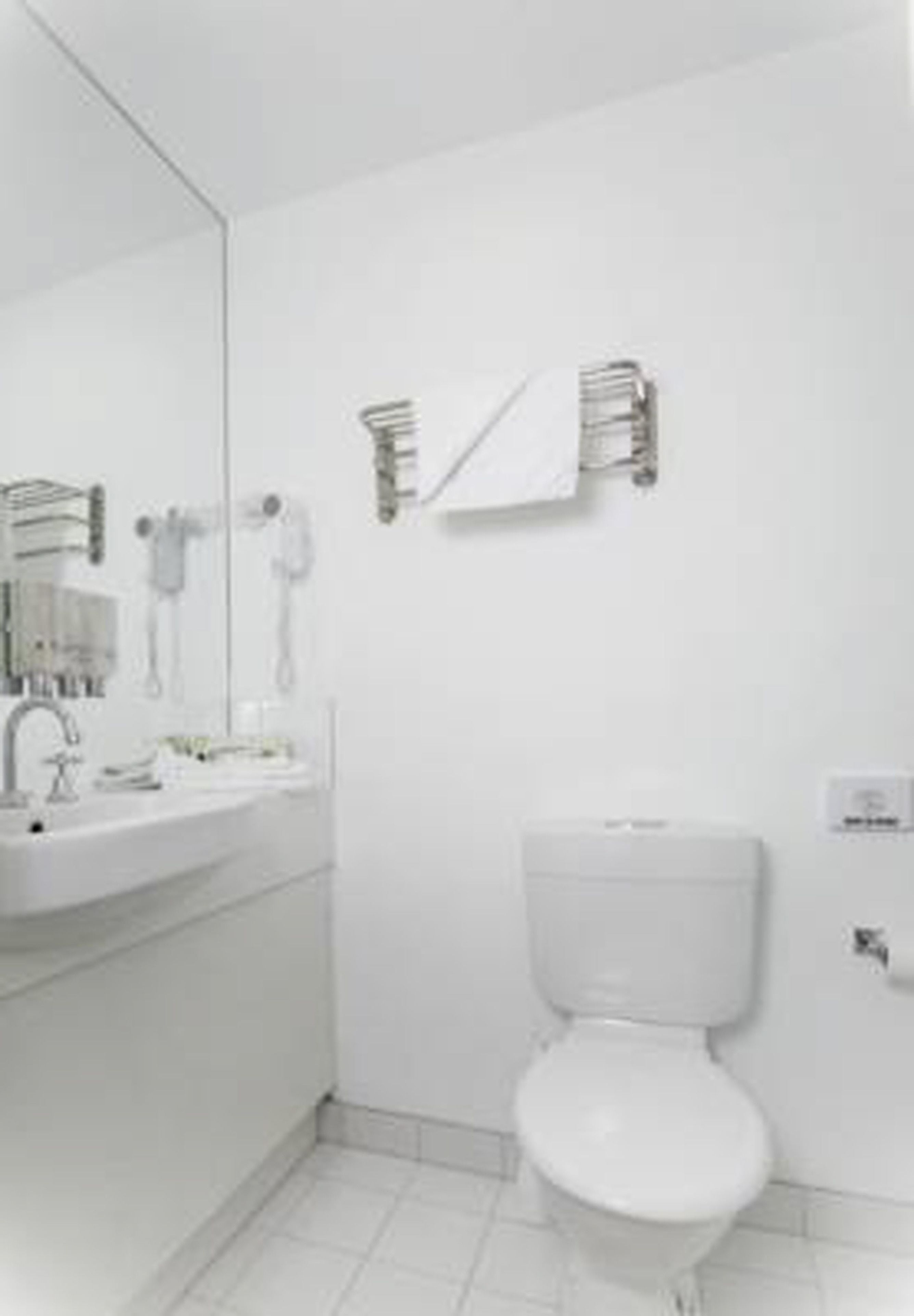 A modern bathroom with a white sink, mirror, and toilet.