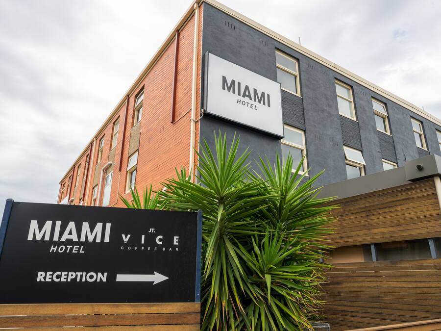 Letrero de hotel que indica el Hotel Miami Vice con una señal que indica la dirección a la recepción.