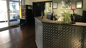 Zona de recepción con mostrador estampado, un reloj y una decoración de flamenco rosa.