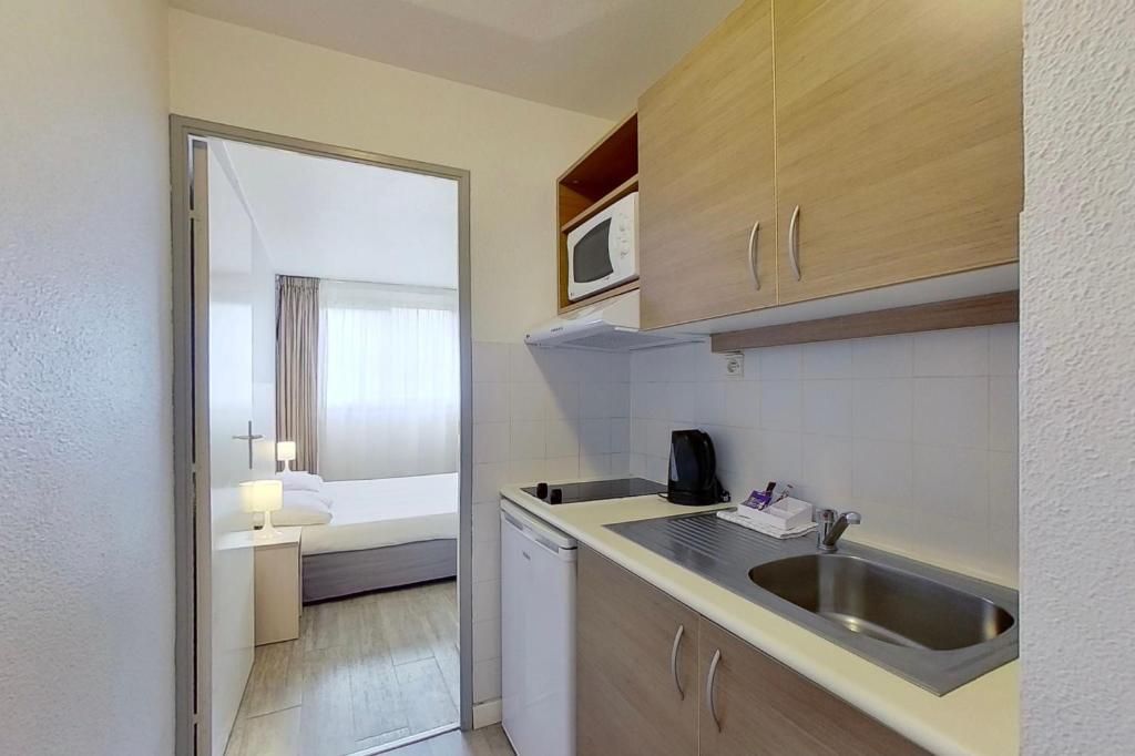 Una kitchenette compacta con microondas, lavamanos y un refrigerador pequeño.