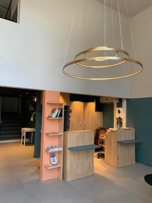 Un interior moderno con un colgante circular, estanterías de madera y una escalera al fondo.