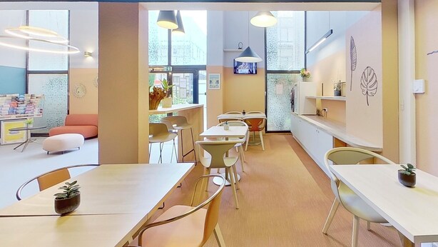 A modern interior with tables and chairs, a reception area with a counter, and decorative wall art. - City Residence Aix En Provence (Aix-en-Provence)