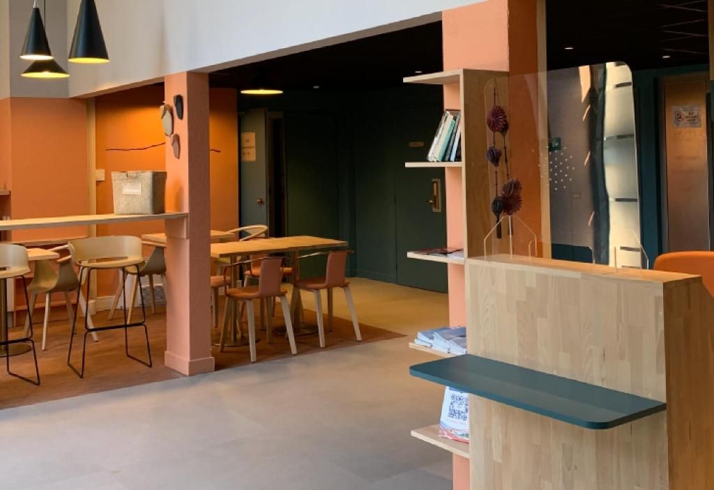 A modern interior with a reception desk, seating area, and a counter with books.