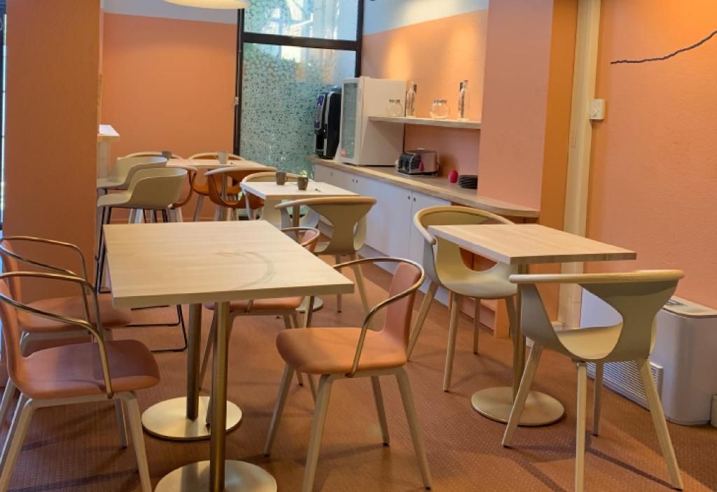 Un'area pranzo con tavoli e sedie, un bancone con elettrodomestici e una finestra vista.