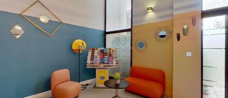 Un interior moderno con una pared azul, muebles naranjas y una pequeña mesa con una planta.