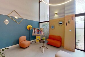 A modern interior with a blue wall, orange furniture, and a small table with a plant. - City Residence Aix En Provence (Aix-en-Provence)