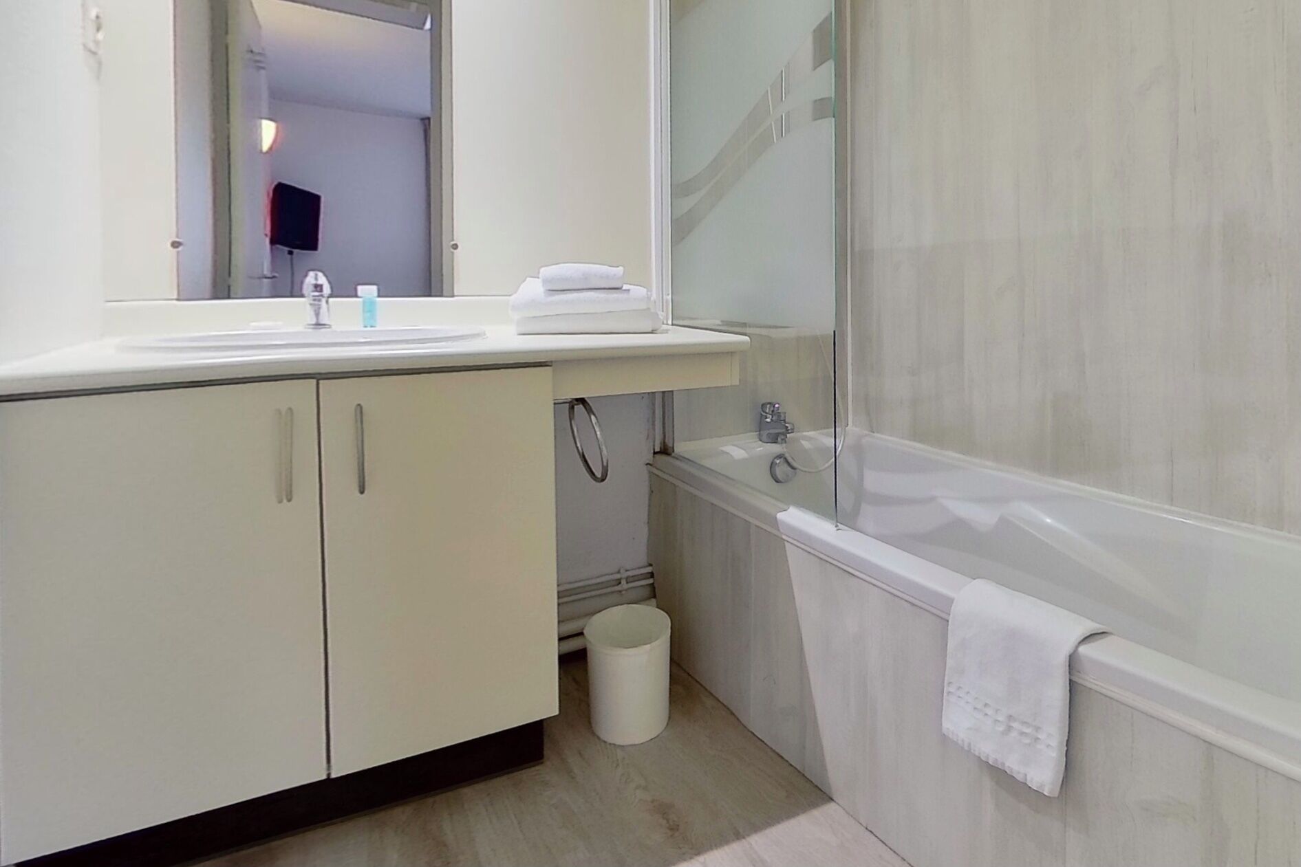 A modern bathroom with a sink, mirror, and bathtub.
