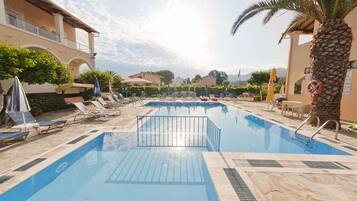 Alberca al aire libre, sombrillas en la alberca y camastros