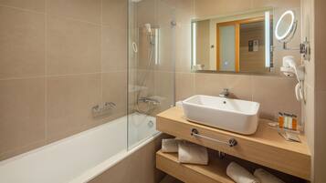 A modern bathroom with a glass-enclosed shower, a white sink, and a vanity with a mirror.