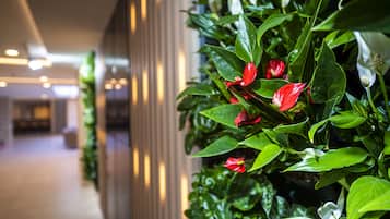 A corridor with a green plant wall and a potted plant with red flowers.