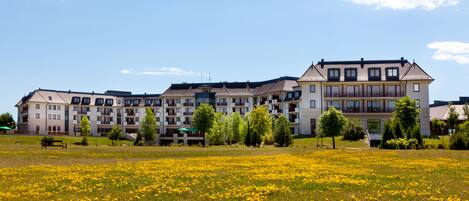 A multi-story hotel with balconies and a large lawn in front.