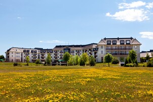 Um hotel com vários andares, varandas e um amplo gramado em frente.