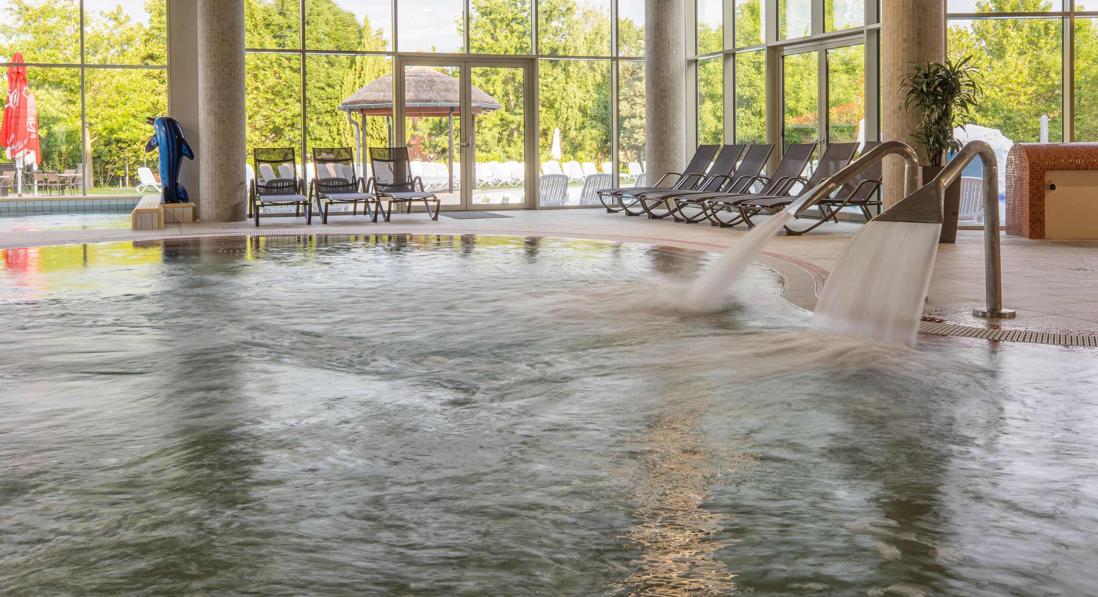 Una piscina interior con sillones de descanso y un pabellón.