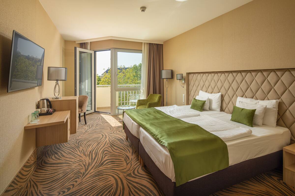Ein Hotelzimmer mit einem großen Bett, einem Schreibtisch, einem Stuhl und einem Balkon mit Blick.