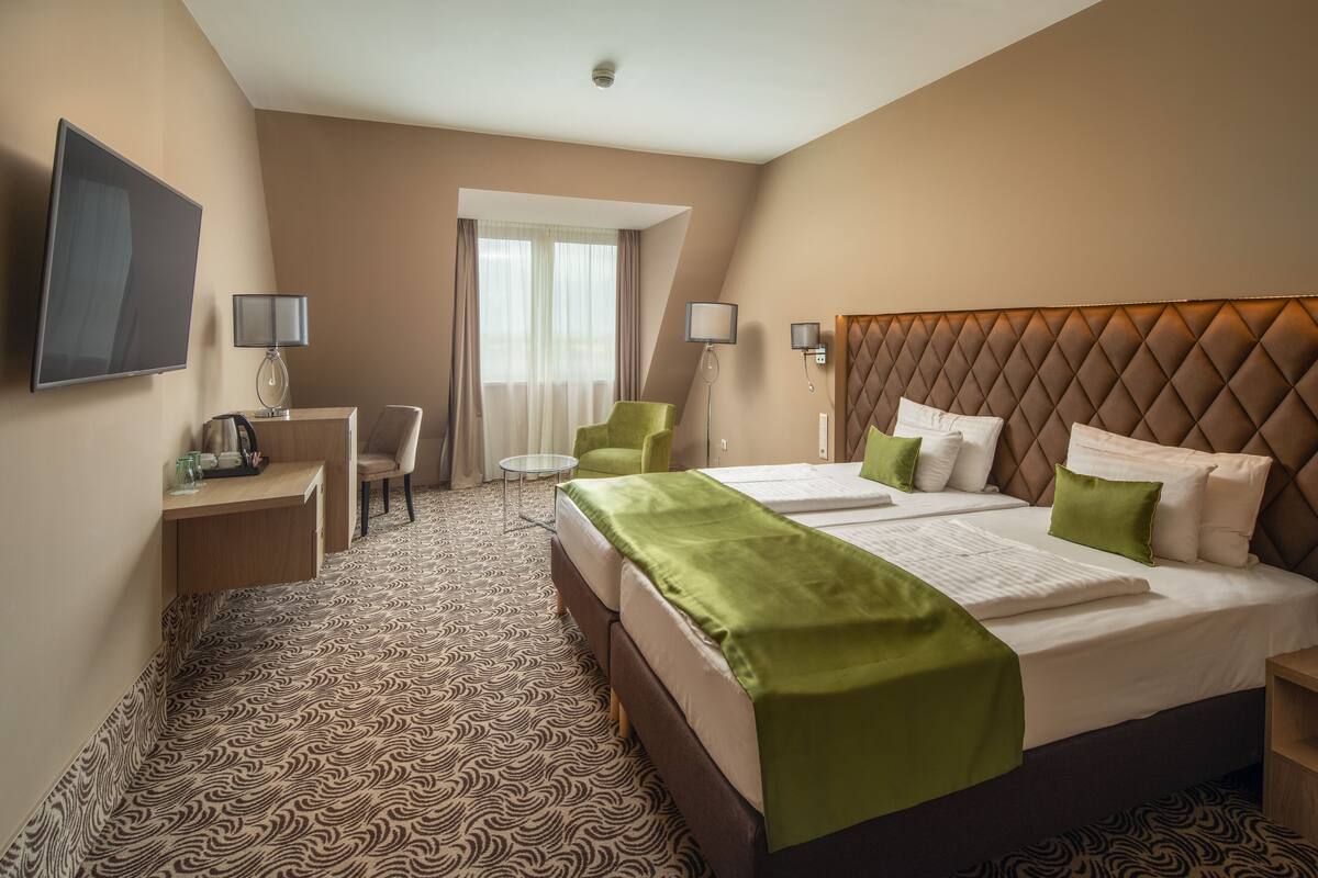 Ein Hotelzimmer mit einem großen Bett, zwei Nachttischen, einem Schreibtisch, einem Stuhl und einem Fernseher.