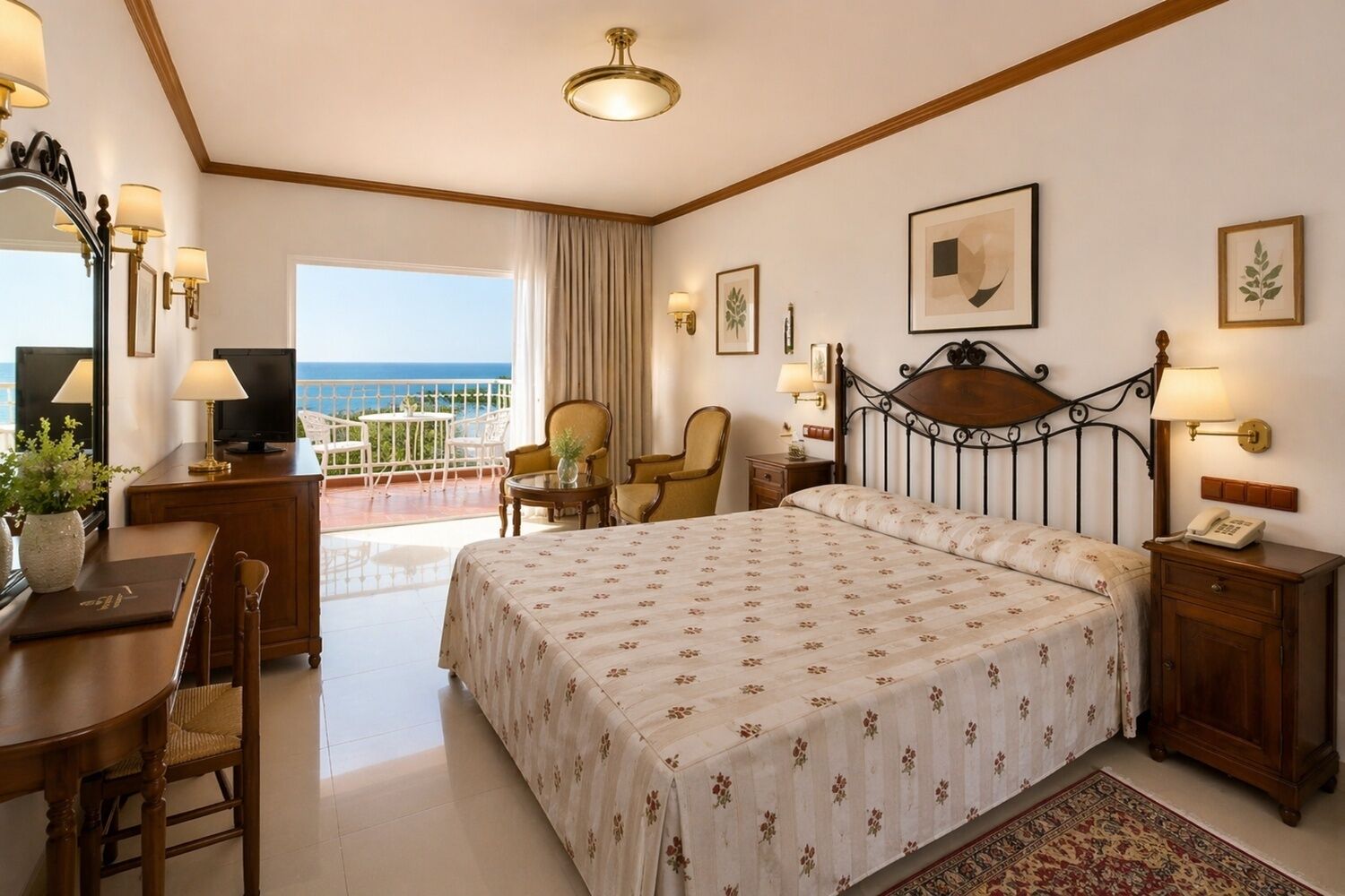 Hotelkamer met een bed, een bureau met lamp, een stoel, een klein tafeltje, een nachtkastje en uitzicht op zee.