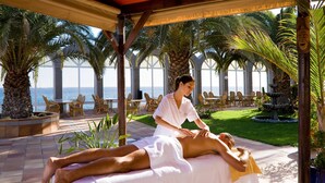 Eine Massageanwendung in einer luxuriösen Wellnessumgebung mit Meerblick.