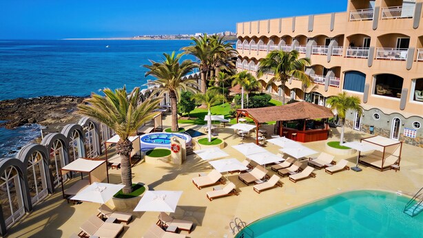 Ein Resort mit Pool, Liegestühlen und Meerblick.