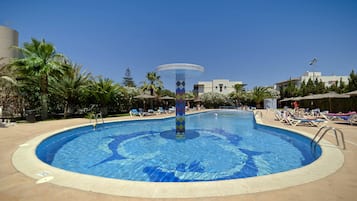 Relax by the pool surrounded by lush greenery and lounge chairs.