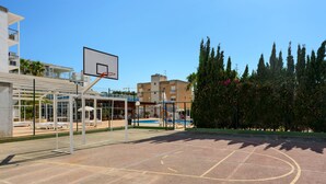 An outdoor basketball court with a net, surrounded by buildings and trees. - Aparthotel Vibra Bay (Sant Antoni de Portmany)