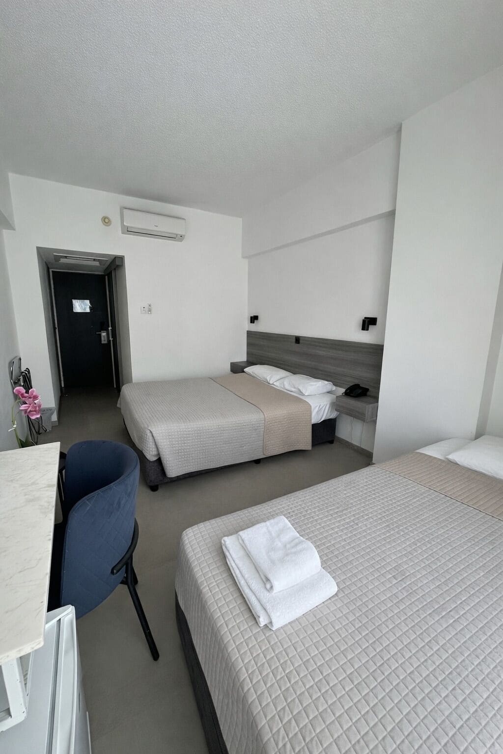 Ein Hotelzimmer mit zwei Betten, einem Schreibtisch und einem Stuhl.
