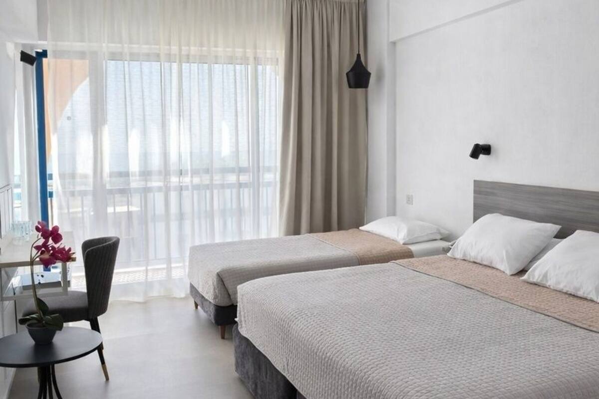 A hotel room with two beds, a desk, and a chair.
