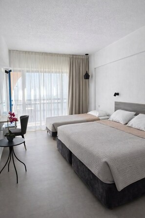 A hotel room with two beds, a desk, and a chair.