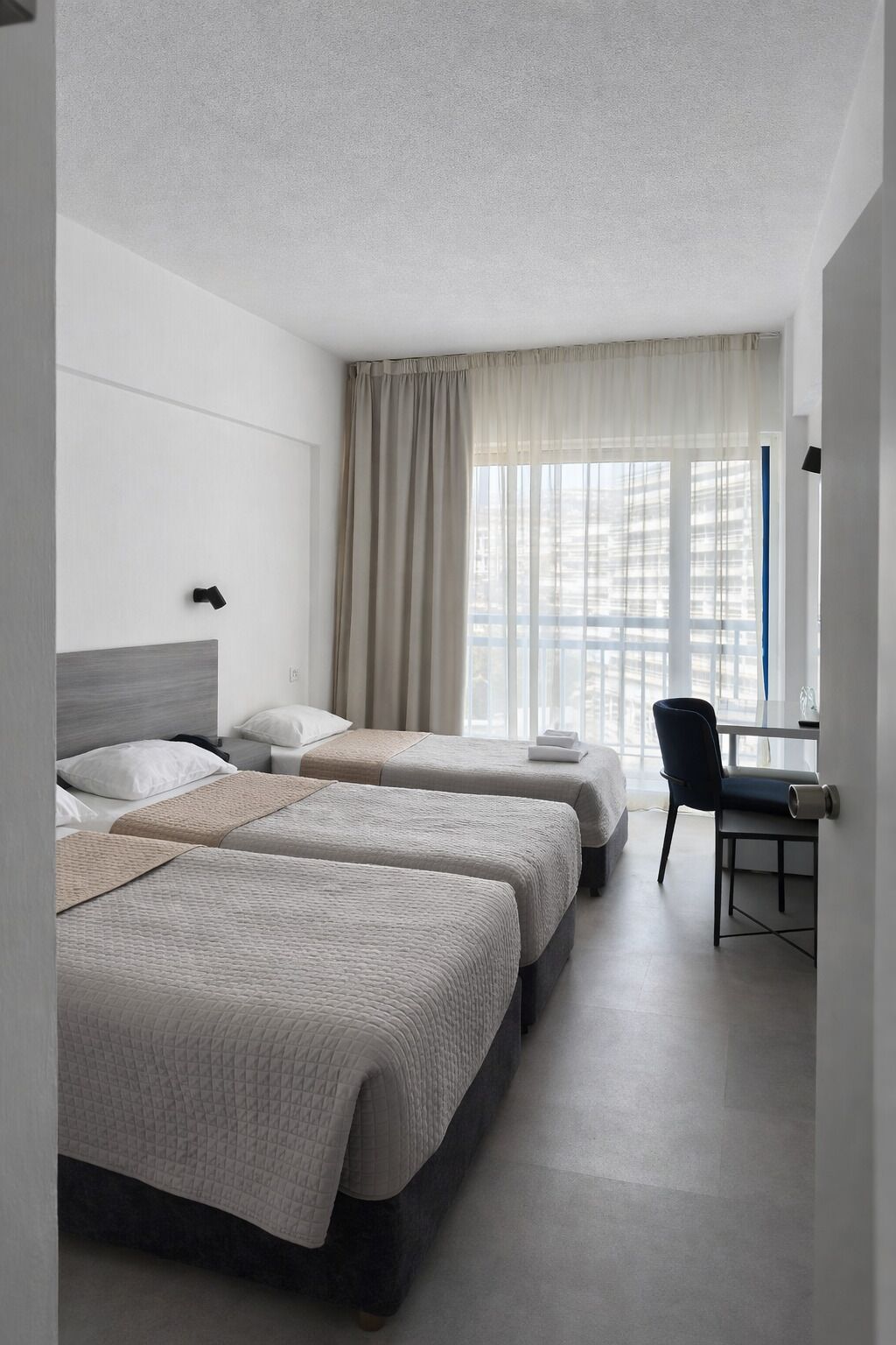 A hotel room with two beds, a desk, and a chair.